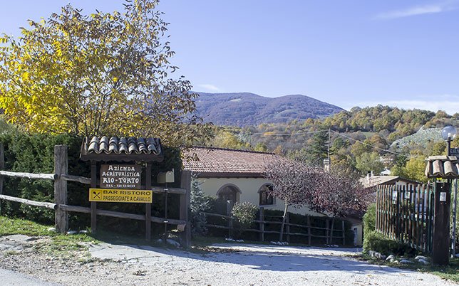 agriturismo-rio-torto-foto-06 Entrata dell’Agriturismo Alfedena Abruzzo immersa nel foliage autunnale, tra legno, monti e accoglienza genuina per esperienze a cavallo e sapori locali.